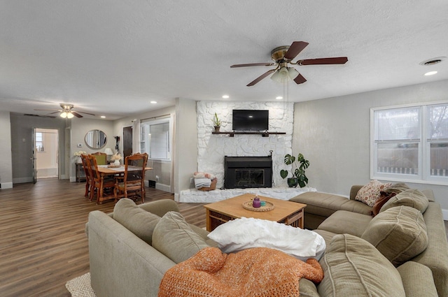 living room with a textured ceiling, a fireplace, dark wood-type flooring, and a wealth of natural light