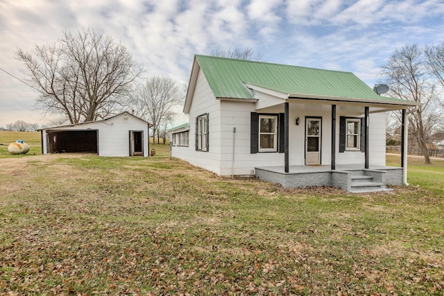 view of front of house with an outbuilding, a garage, a porch, and a front yard