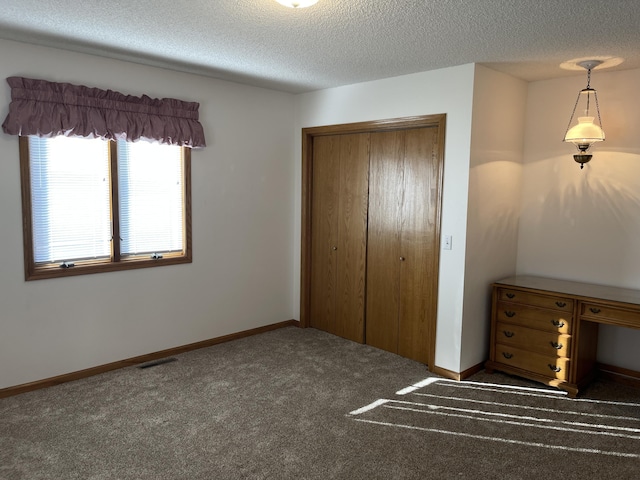 unfurnished bedroom featuring a closet, dark carpet, and a textured ceiling