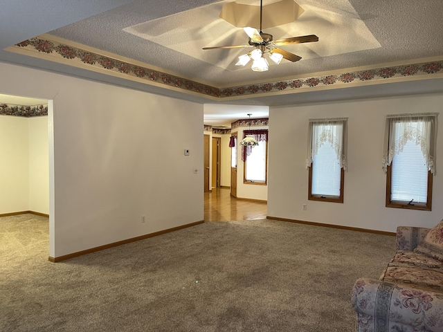 unfurnished living room with carpet flooring, ceiling fan, a raised ceiling, and a textured ceiling