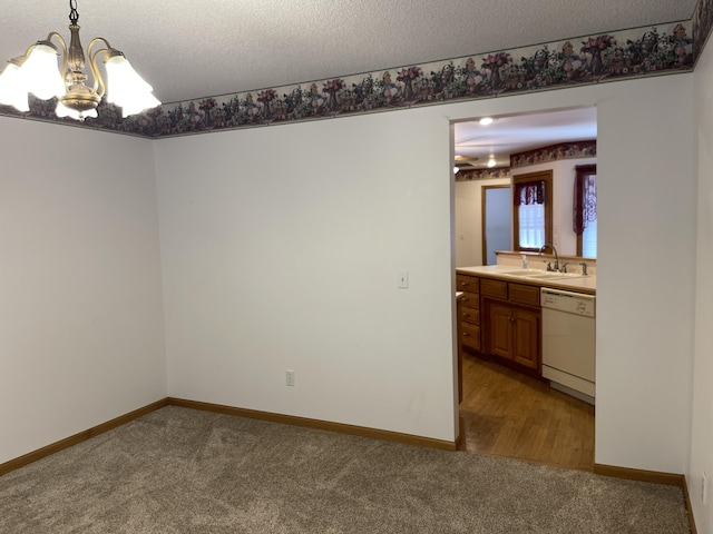 unfurnished room featuring carpet, a textured ceiling, a notable chandelier, and sink