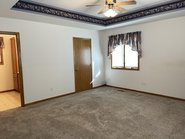 unfurnished room with ceiling fan, a textured ceiling, and light carpet