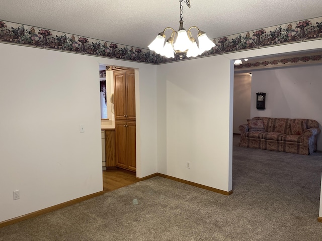 carpeted empty room featuring a textured ceiling and an inviting chandelier