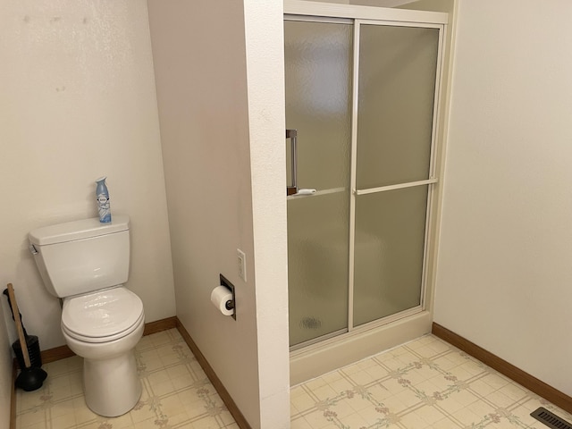 bathroom featuring toilet and a shower with shower door