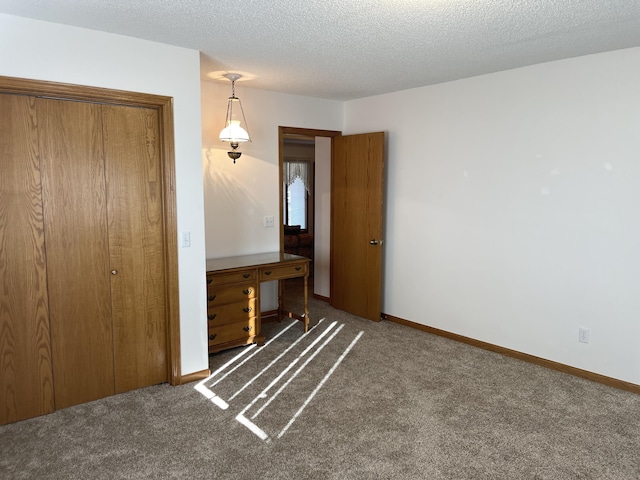 unfurnished bedroom with a textured ceiling, dark carpet, and a closet