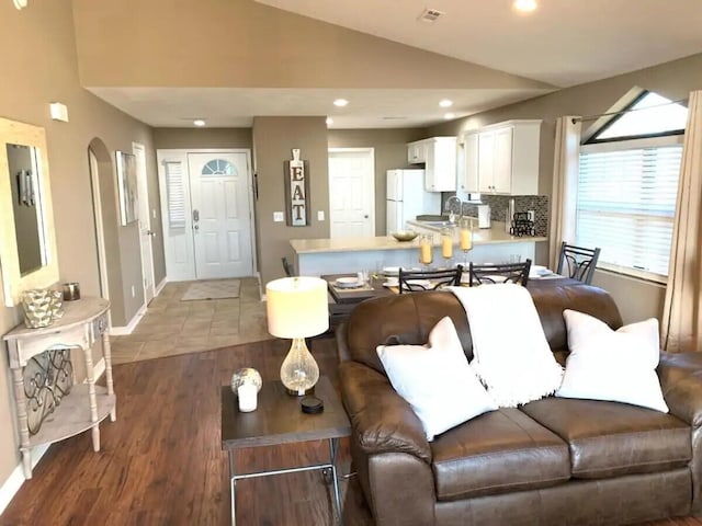 living room featuring dark hardwood / wood-style floors, sink, and vaulted ceiling