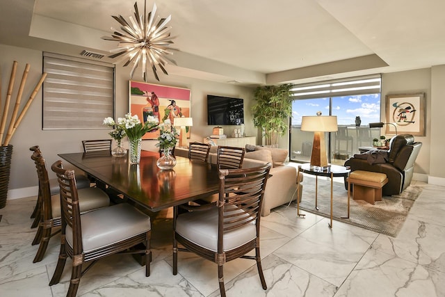 dining space with a tray ceiling and a chandelier