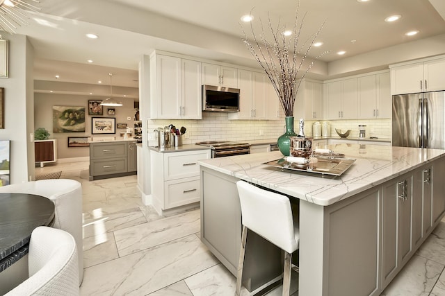 kitchen with a large island, white cabinetry, stainless steel appliances, and tasteful backsplash