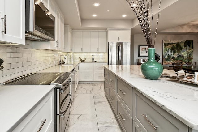 kitchen featuring white cabinetry, sink, stainless steel appliances, light stone counters, and gray cabinets