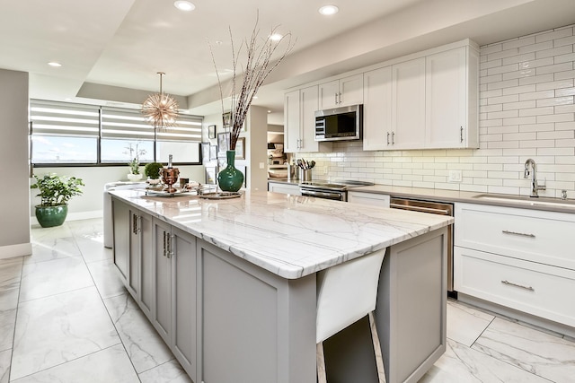 kitchen with white cabinets, a center island, stainless steel appliances, and sink