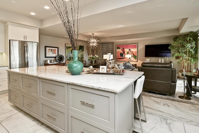 kitchen featuring decorative light fixtures, a kitchen island, light stone counters, and high quality fridge