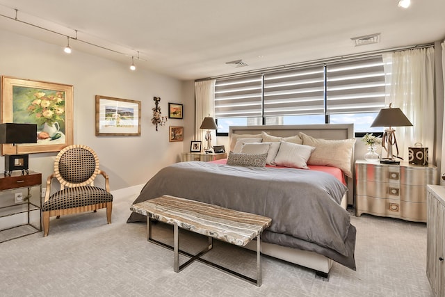 carpeted bedroom featuring rail lighting and multiple windows