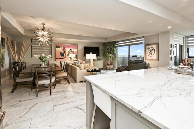 kitchen featuring decorative light fixtures, light stone countertops, a tray ceiling, and a chandelier