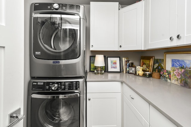 laundry area with cabinets and stacked washer / dryer