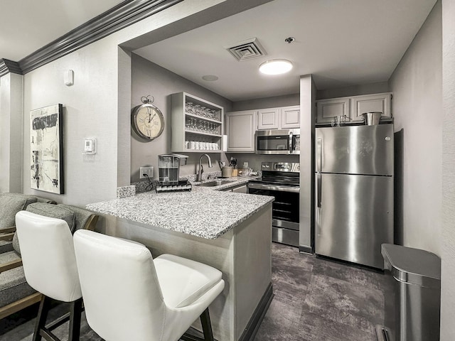 kitchen with sink, a kitchen breakfast bar, light stone counters, kitchen peninsula, and appliances with stainless steel finishes