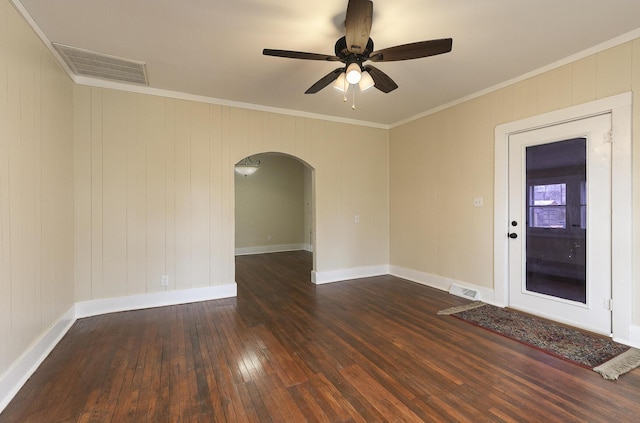 empty room featuring ceiling fan, dark wood-type flooring, wood walls, and ornamental molding