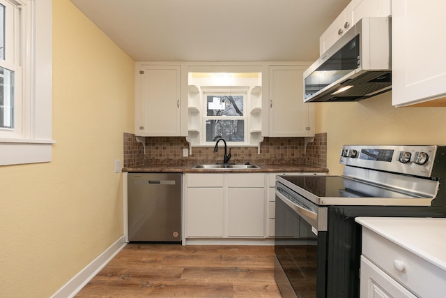 kitchen featuring decorative backsplash, stainless steel appliances, sink, wood-type flooring, and white cabinetry