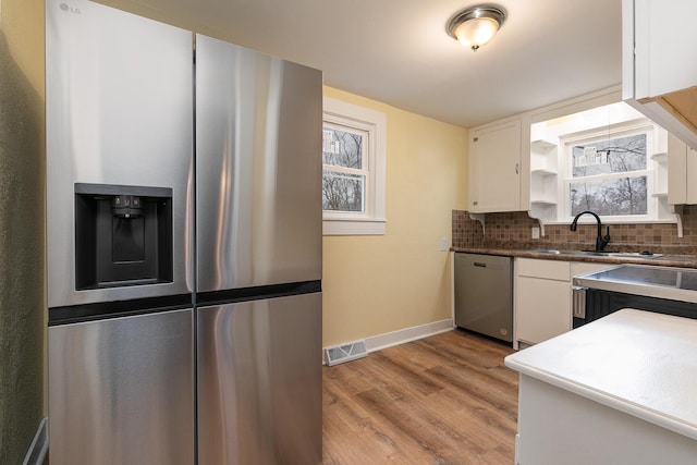 kitchen featuring white cabinetry, sink, tasteful backsplash, appliances with stainless steel finishes, and light wood-type flooring