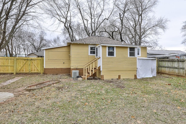 back of property featuring a lawn and central air condition unit