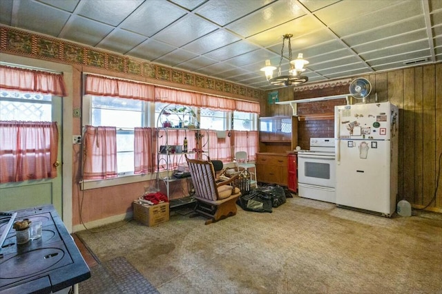 kitchen featuring wood walls, plenty of natural light, a chandelier, and white appliances