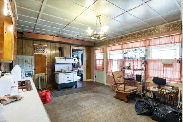 interior space featuring carpet flooring, radiator heating unit, an inviting chandelier, and wood walls