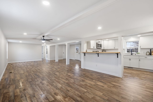 unfurnished living room with beam ceiling, hardwood / wood-style flooring, ceiling fan, and sink