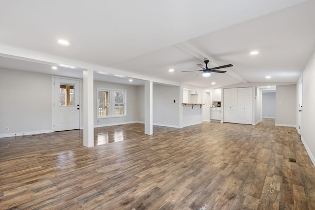 unfurnished living room featuring ceiling fan, lofted ceiling with beams, and dark hardwood / wood-style floors