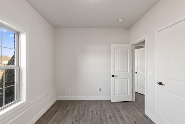 unfurnished bedroom with wood-type flooring and multiple windows