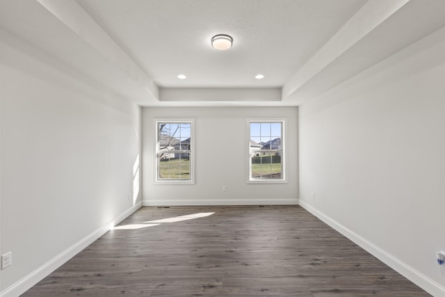 empty room featuring a tray ceiling and dark hardwood / wood-style floors