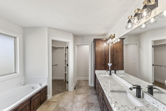 bathroom featuring tile patterned flooring, a textured ceiling, vanity, and a tub