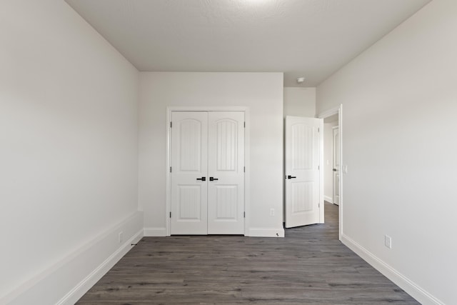 unfurnished bedroom featuring dark hardwood / wood-style flooring and a closet