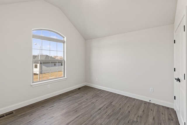 empty room with hardwood / wood-style flooring and lofted ceiling