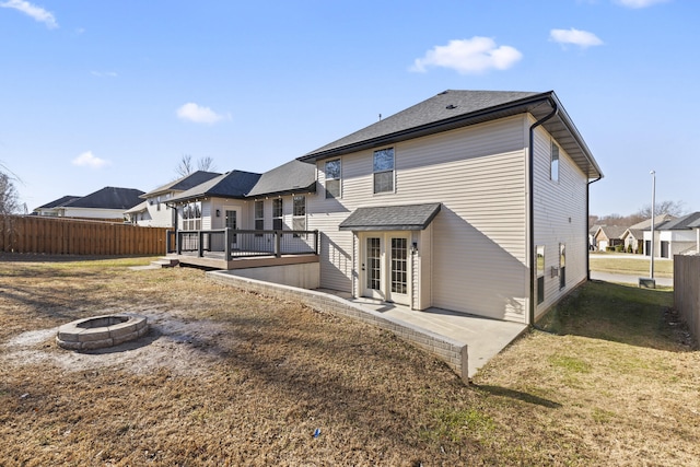 rear view of property featuring a lawn, a wooden deck, and a fire pit