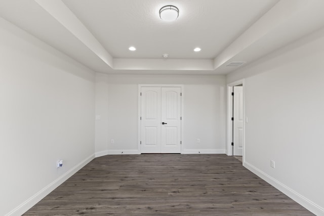 unfurnished bedroom with dark hardwood / wood-style flooring, a raised ceiling, and a closet