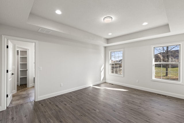 spare room with dark hardwood / wood-style floors and a tray ceiling