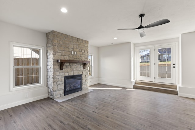 unfurnished living room featuring a stone fireplace, ceiling fan, and hardwood / wood-style flooring