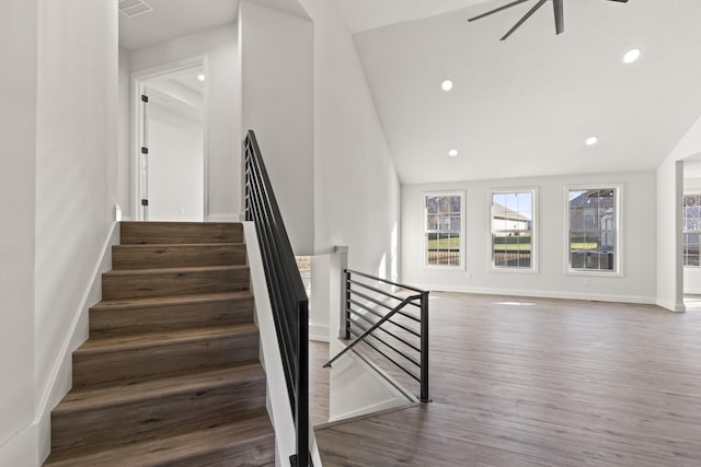 stairway featuring ceiling fan, wood-type flooring, and lofted ceiling