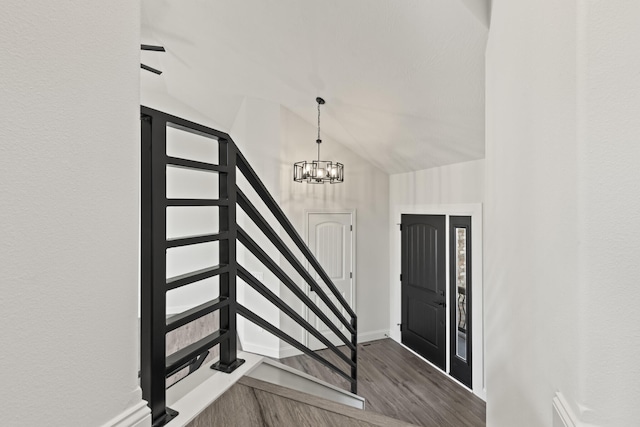 foyer entrance with dark hardwood / wood-style flooring, lofted ceiling, and an inviting chandelier