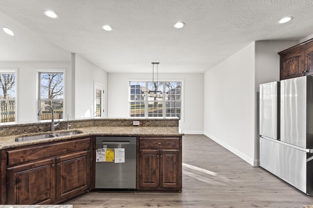 kitchen with pendant lighting, sink, light stone countertops, a notable chandelier, and stainless steel appliances