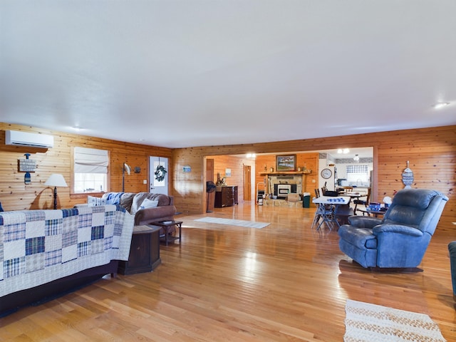 living room with a wall mounted air conditioner, light hardwood / wood-style floors, and wood walls