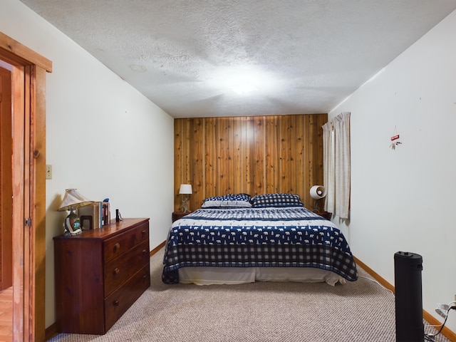 bedroom with carpet flooring, wood walls, and a textured ceiling