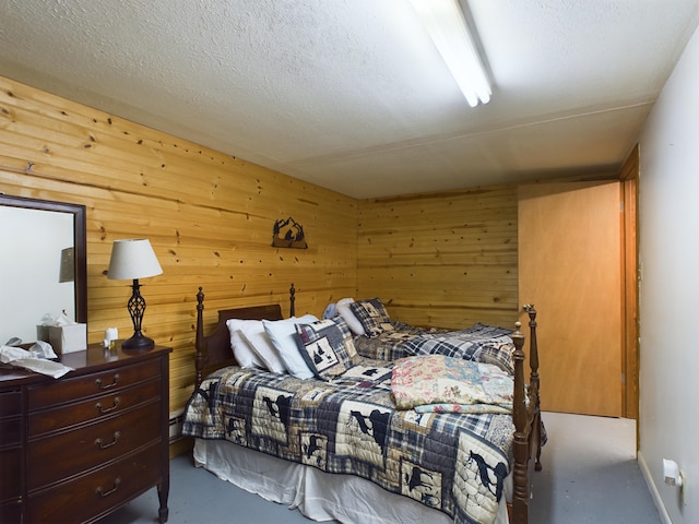 bedroom with wood walls, a textured ceiling, and concrete floors