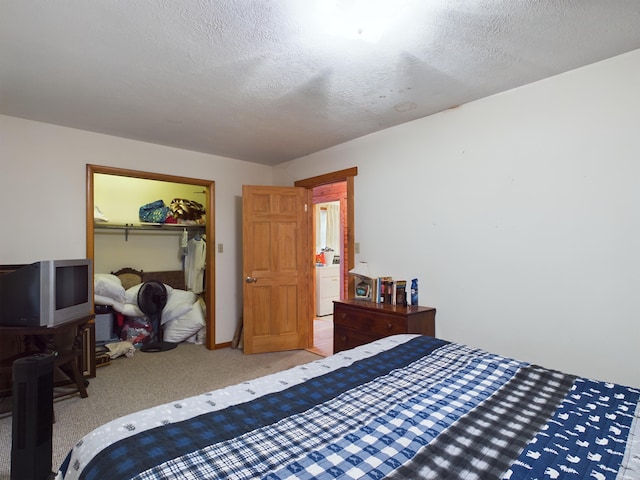 carpeted bedroom featuring a spacious closet, a textured ceiling, washer / clothes dryer, and a closet