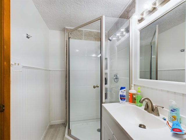 bathroom featuring vanity, an enclosed shower, a textured ceiling, and hardwood / wood-style flooring