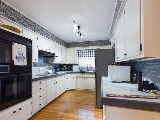 kitchen featuring rail lighting, light hardwood / wood-style flooring, backsplash, white cabinets, and black appliances