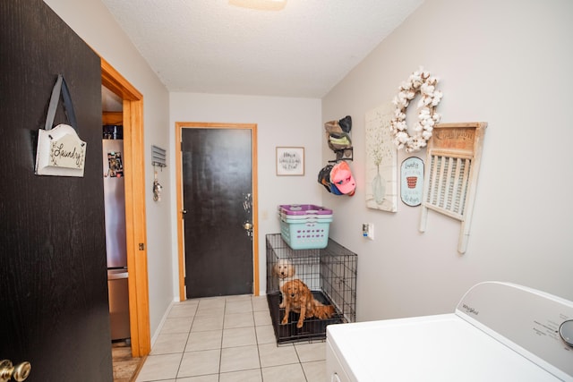 laundry room featuring washer / clothes dryer, light tile patterned flooring, and a textured ceiling