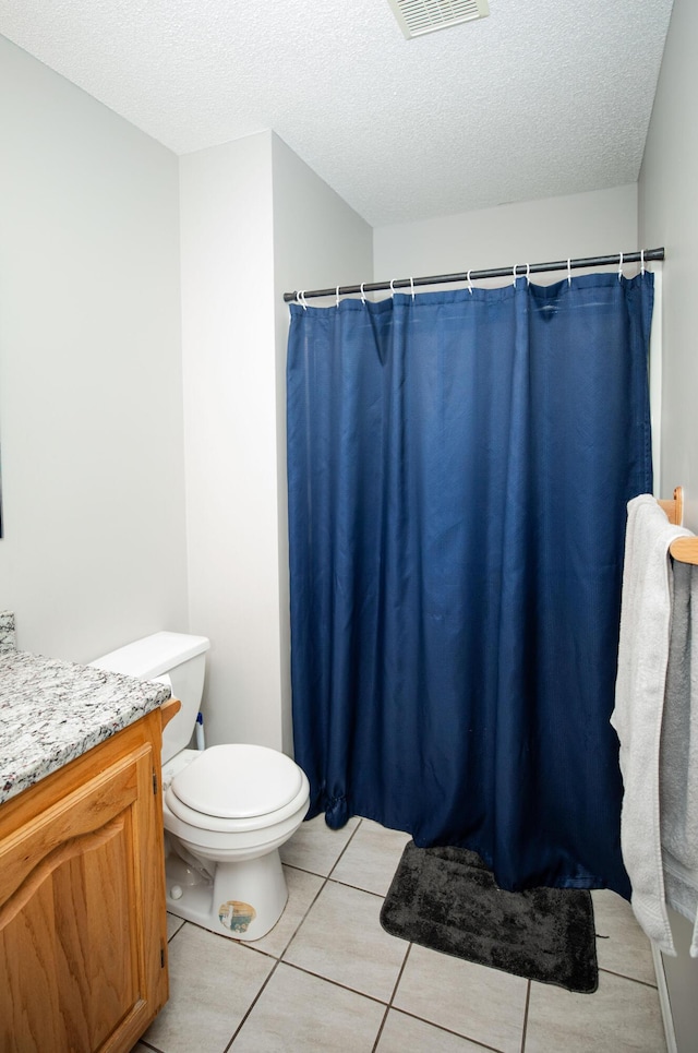 bathroom featuring tile patterned flooring, vanity, toilet, and a textured ceiling