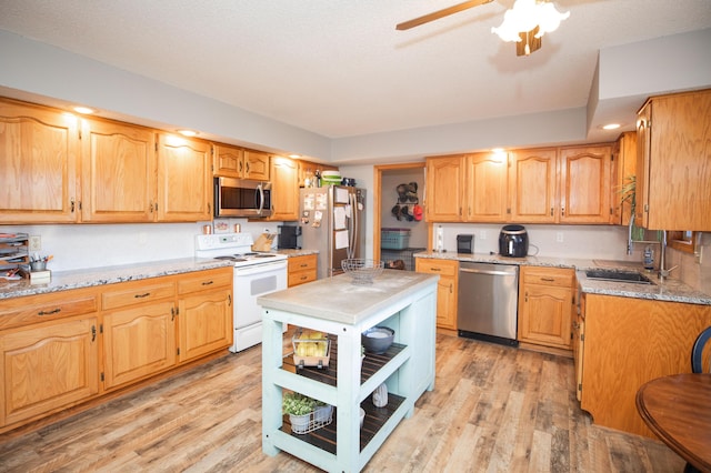 kitchen with ceiling fan, light stone counters, appliances with stainless steel finishes, and light hardwood / wood-style flooring