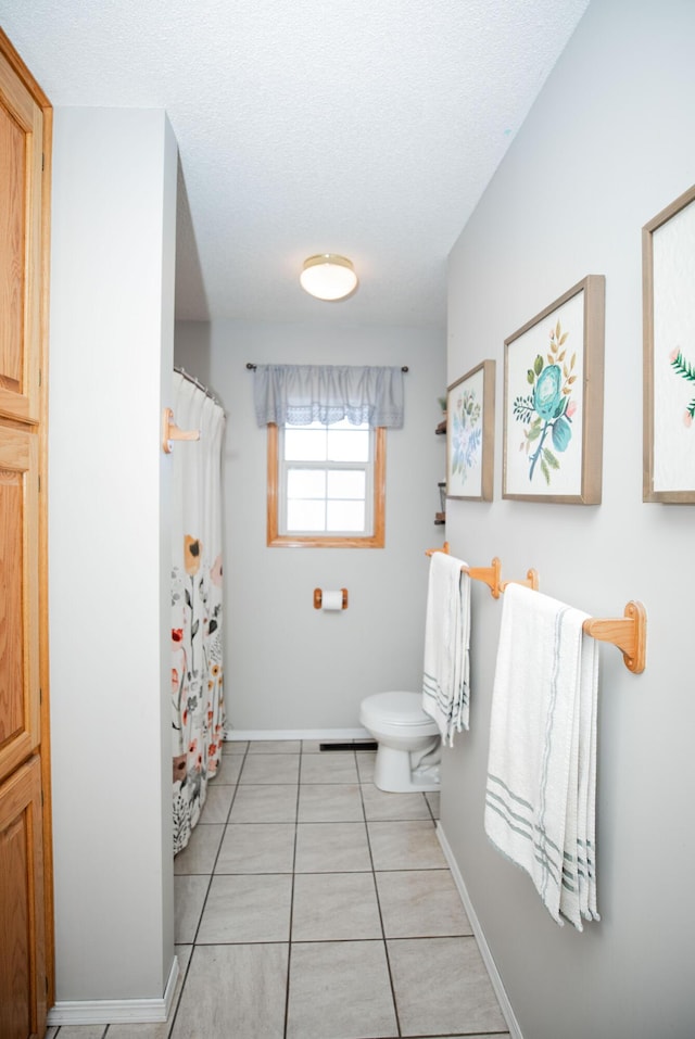 bathroom featuring toilet, a textured ceiling, and tile patterned floors