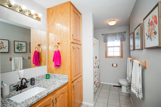 bathroom with tile patterned floors, vanity, a textured ceiling, and toilet